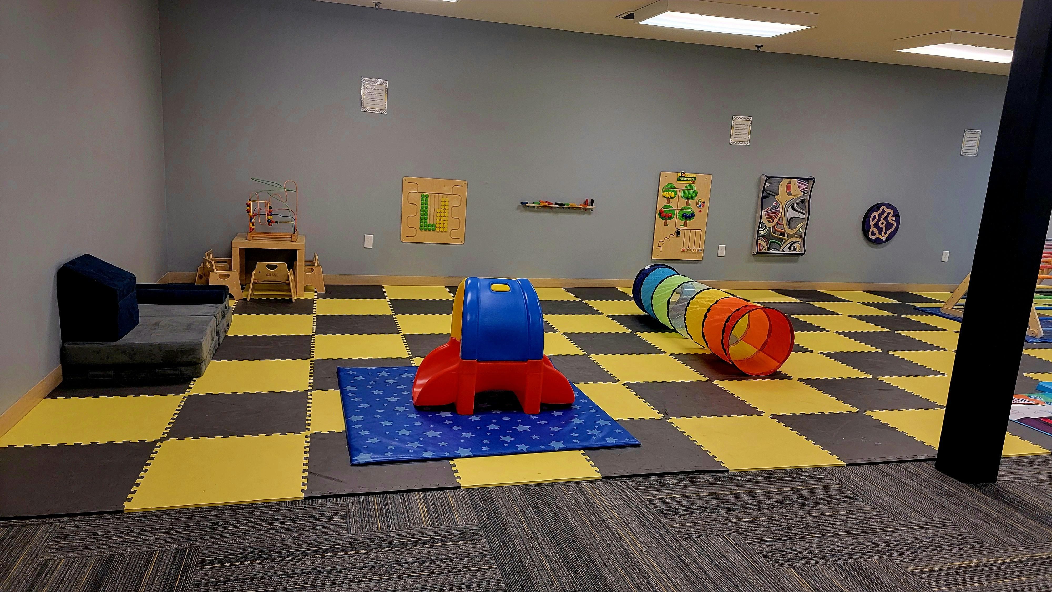 Playroom with checkered floor, small slide, and play tunnel