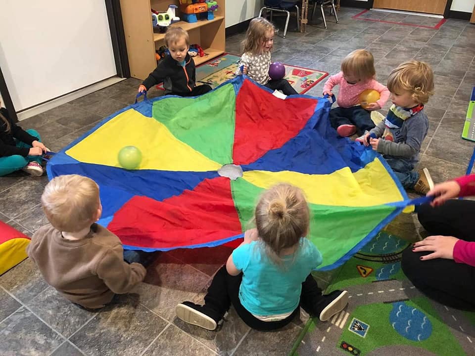 Children playing with a colorful parachute and ball