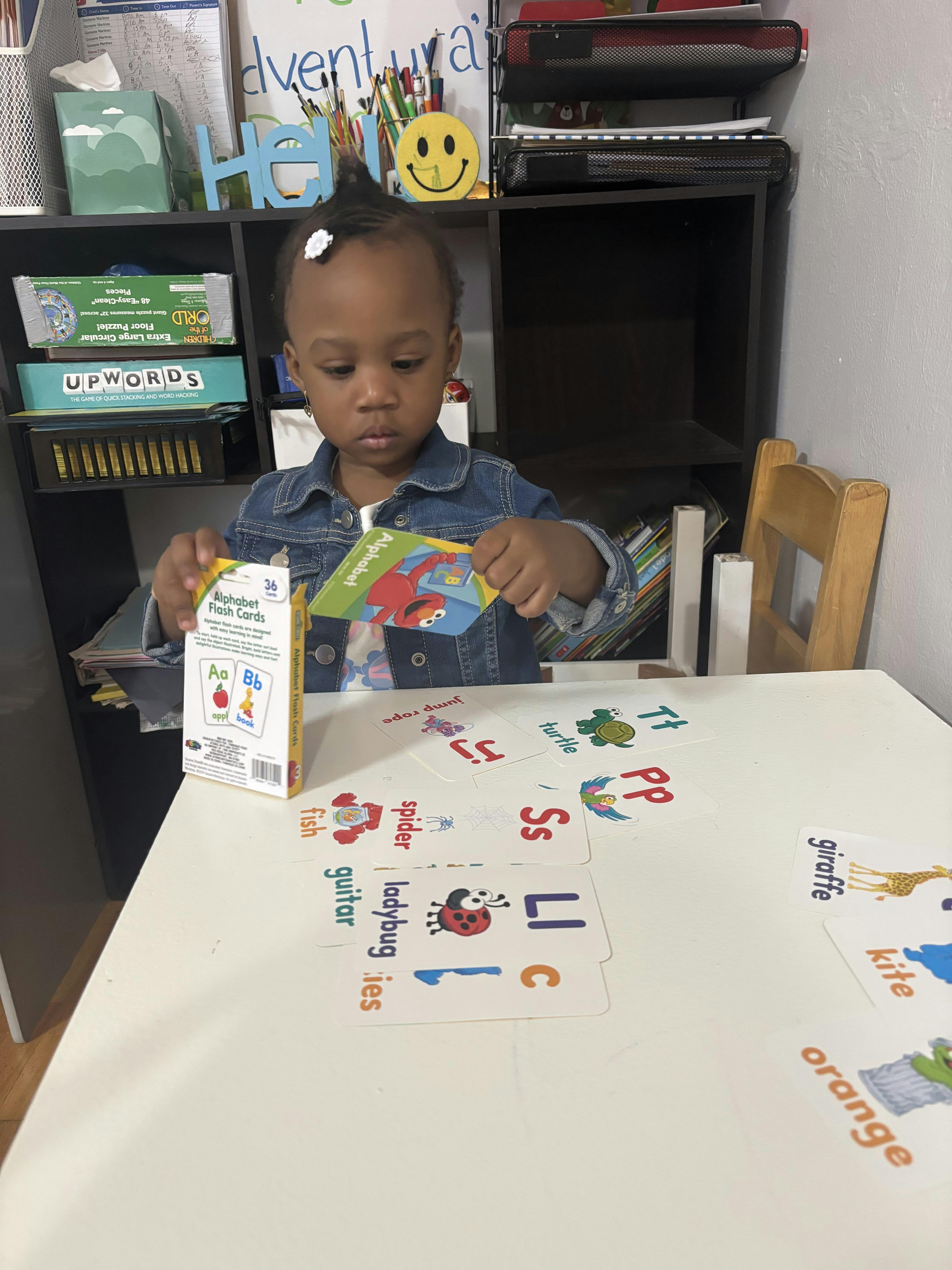Child sitting at a desk playing with alphabet flashcards