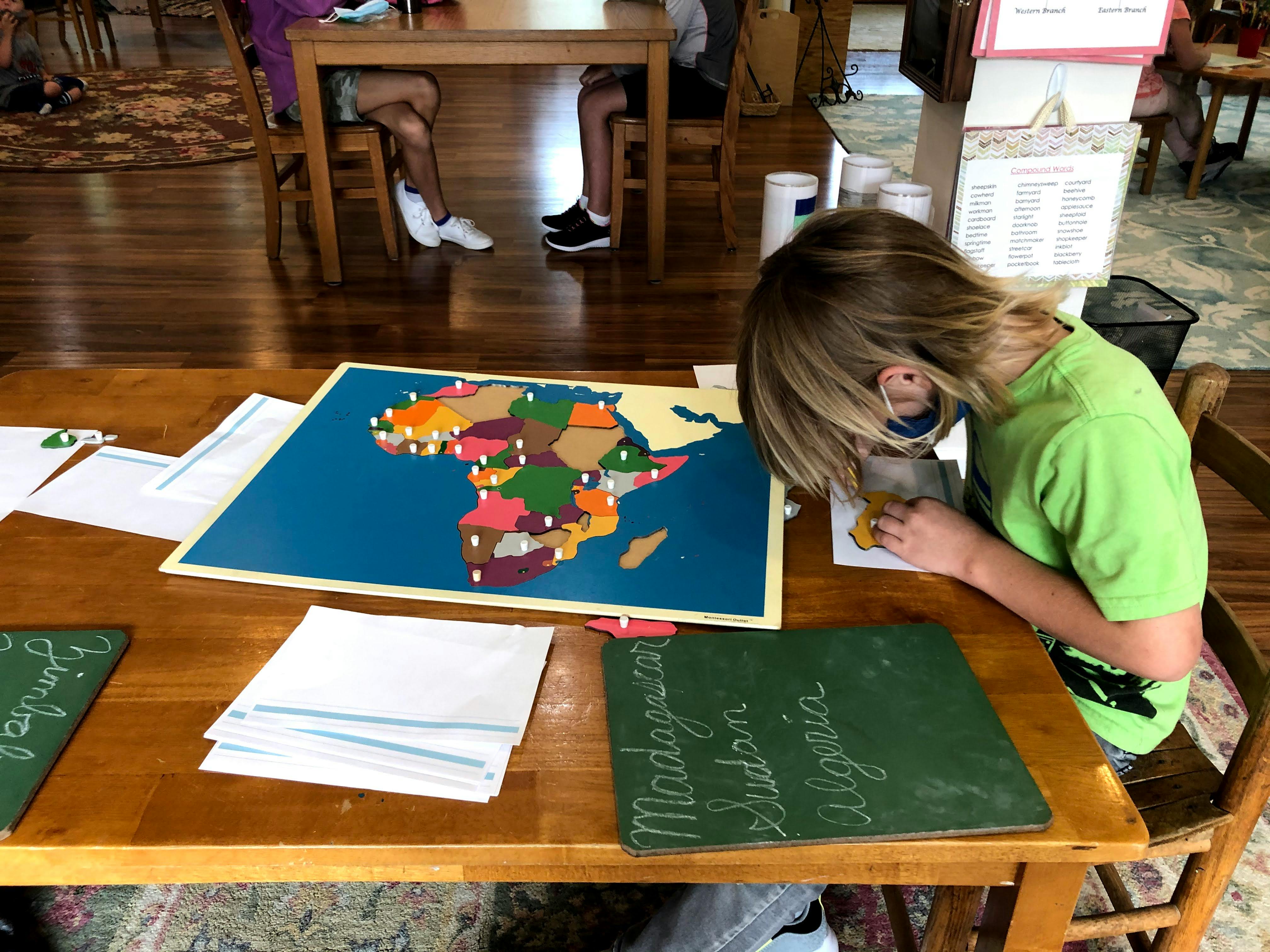 Child working on a puzzle map of Africa at a table