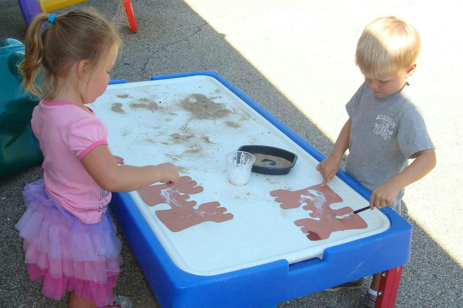Two children playing at a sand and water table