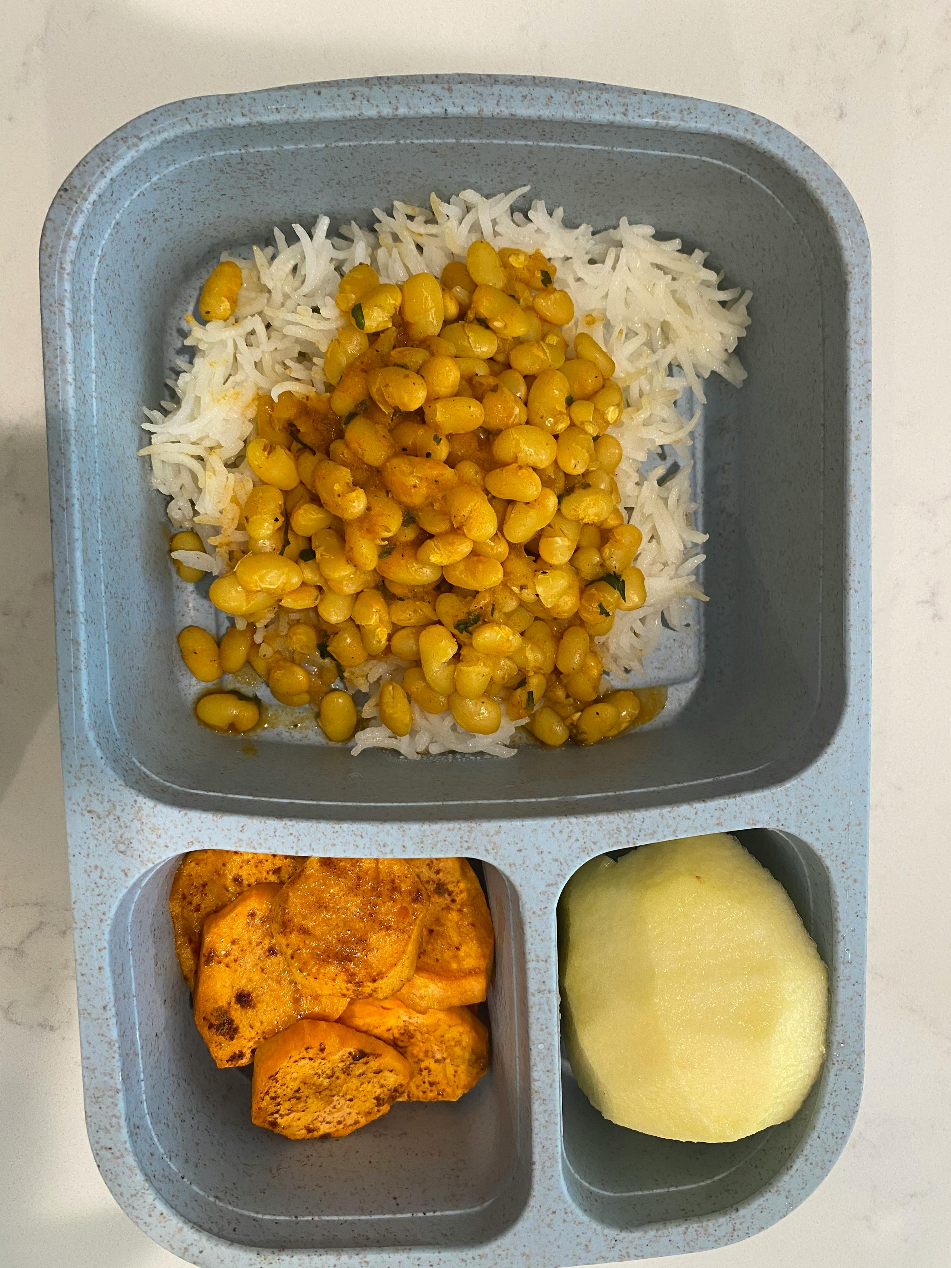 Bento box with rice and beans, sweet potato, and peeled apple
