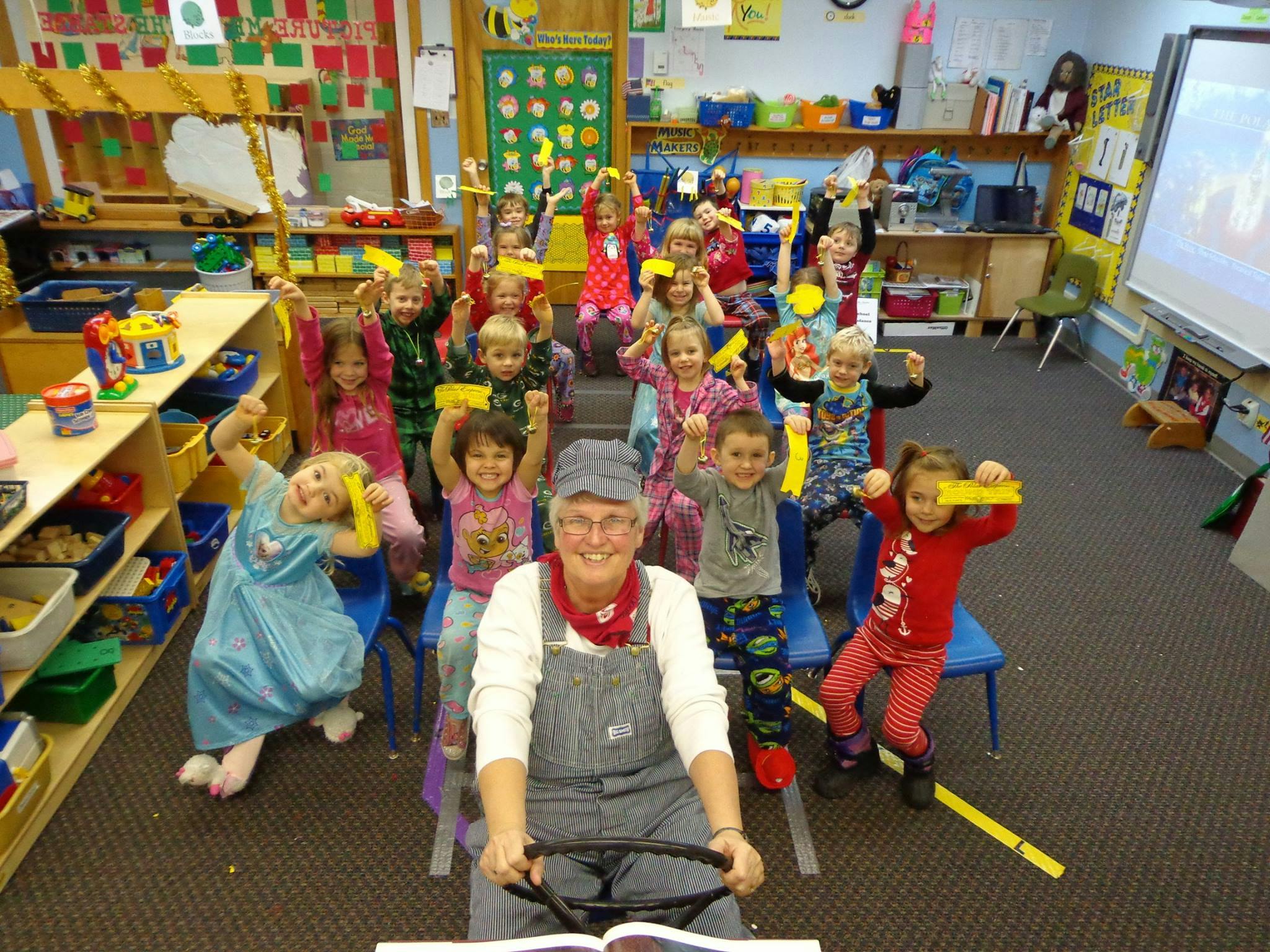 Person in overalls with children in a classroom