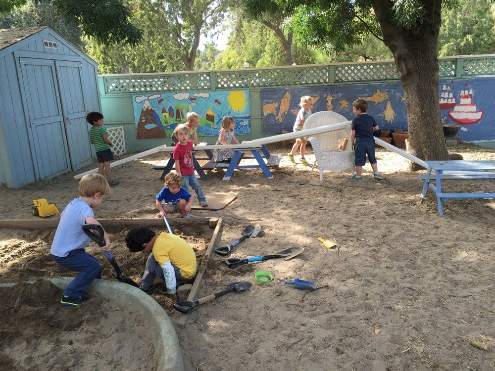 Children playing in a sandbox and on a seesaw in a playground