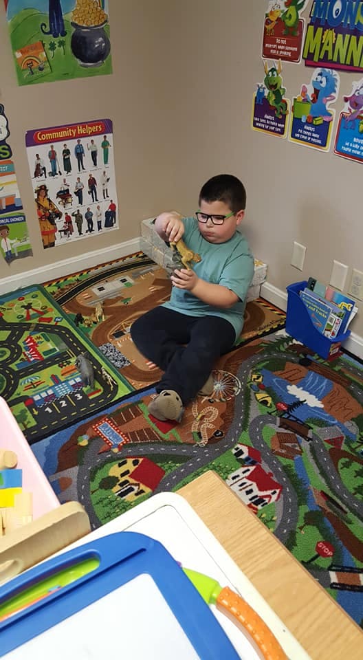 Child sitting on a playmat, holding a toy