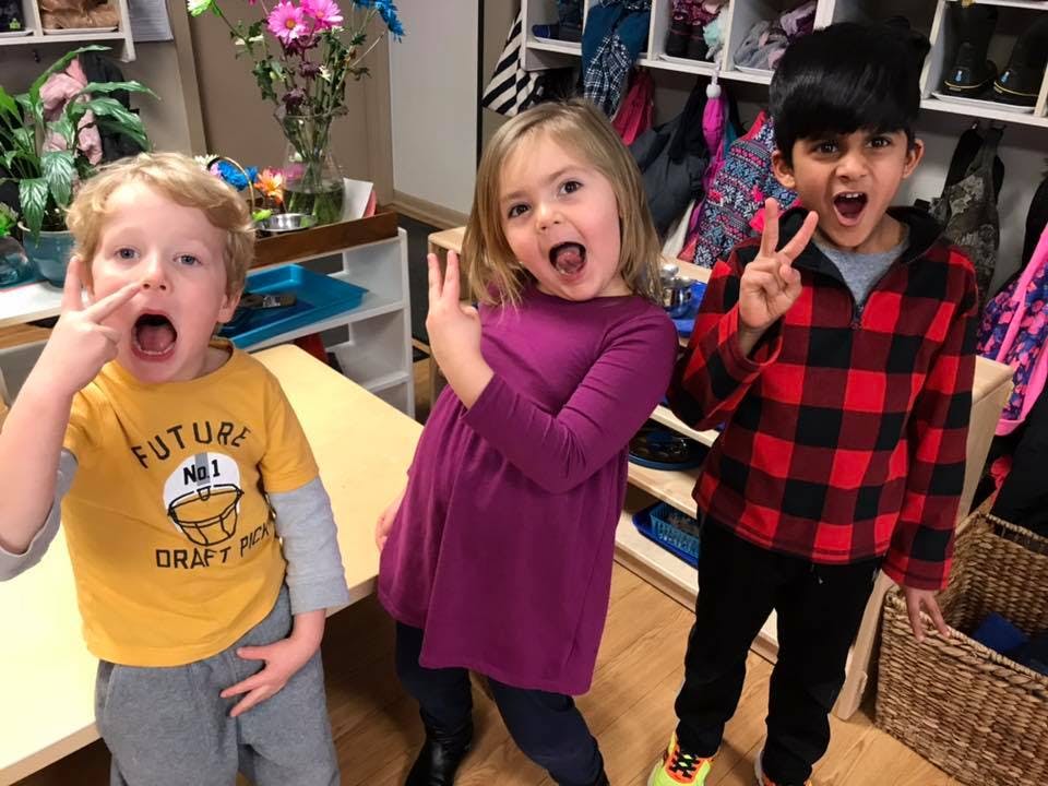 Three children making faces and hand gestures