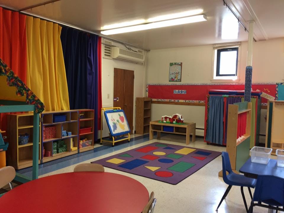 Classroom with colorful curtains, a shape rug, and small tables