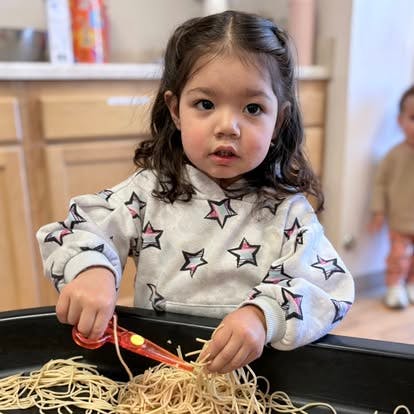 Child cutting noodles with scissors