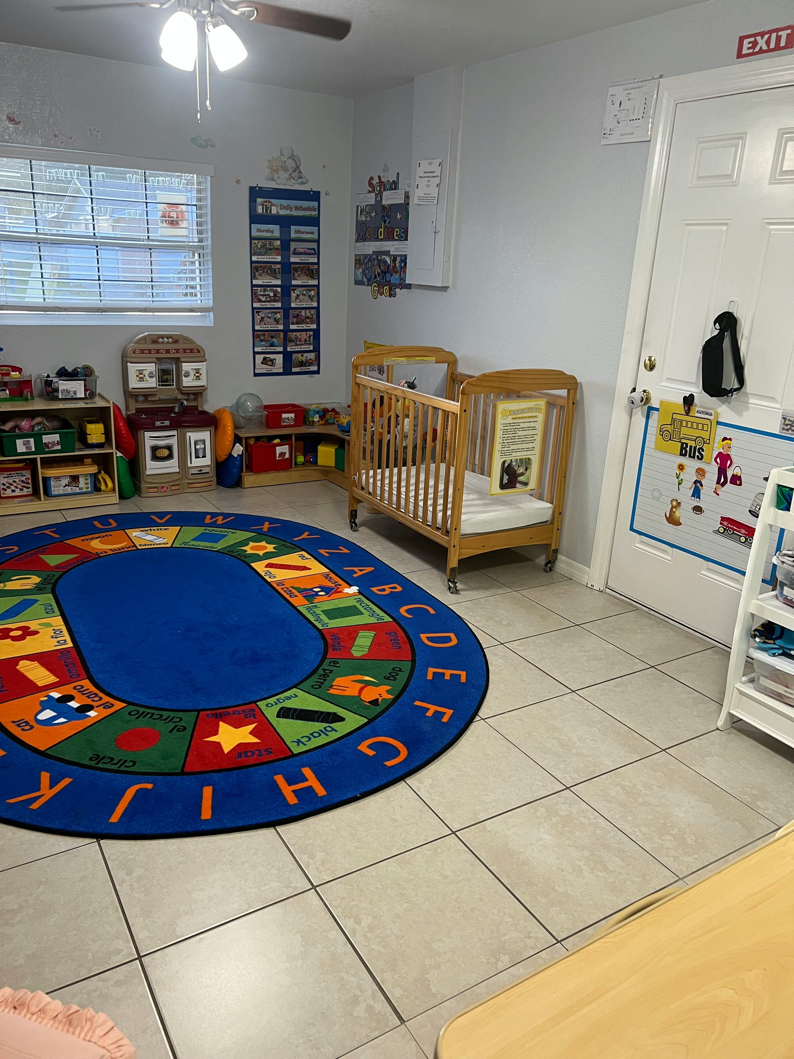 A room with a crib, an alphabet rug, and shelves with toys