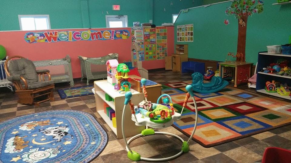 Playroom with colorful rugs, toys, and a "Welcome" sign