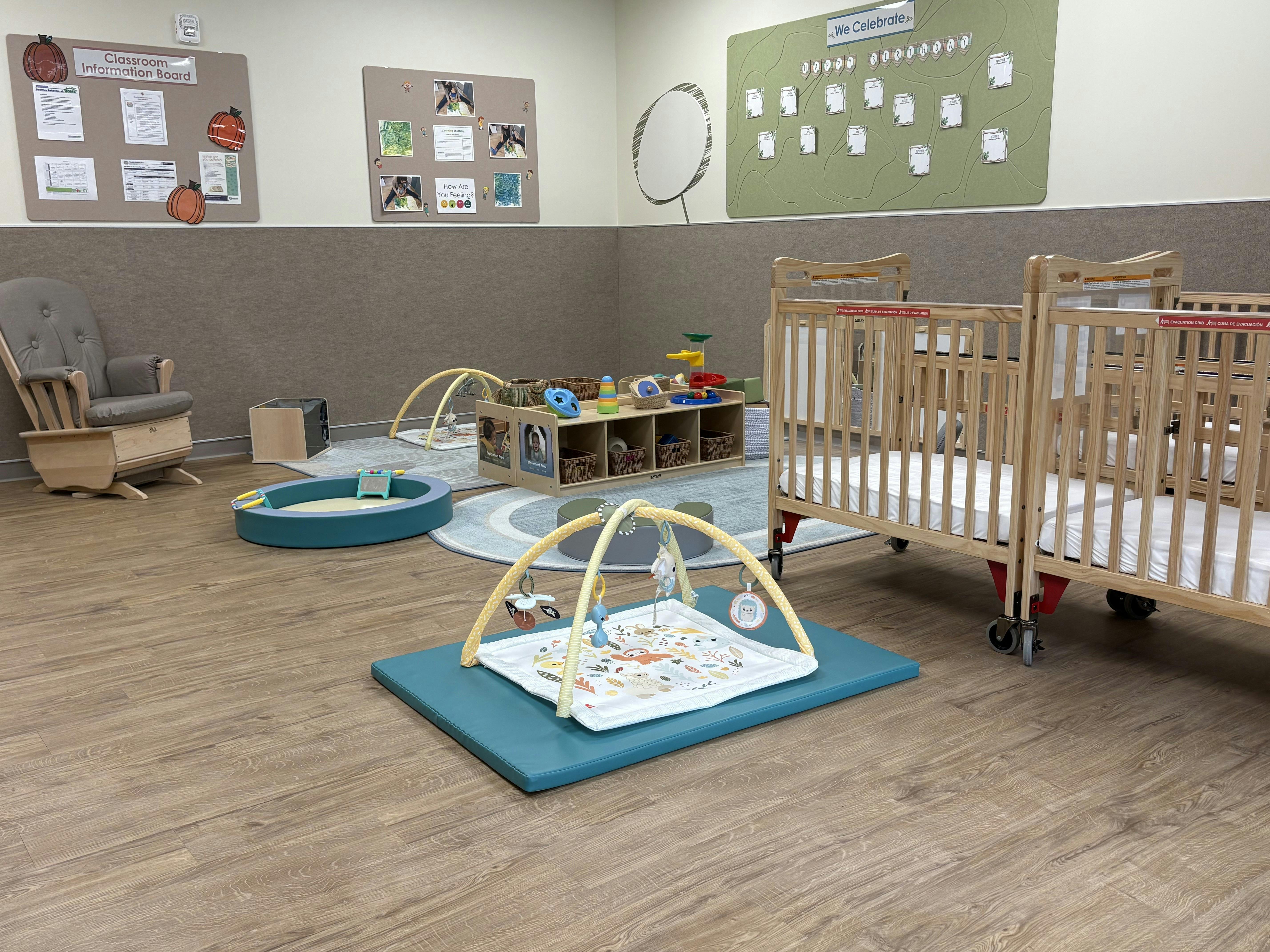 Infant room with cribs, play mats, and a rocking chair