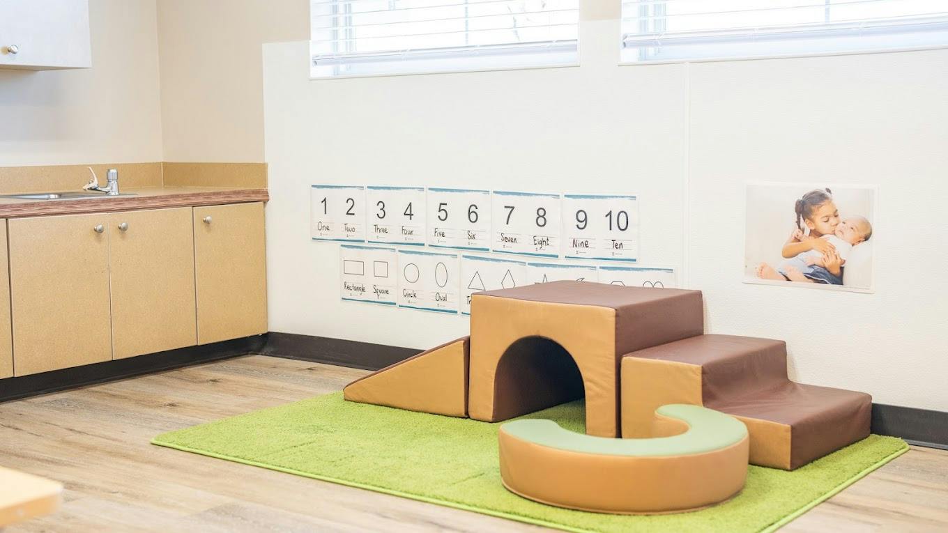 Soft foam play furniture on a green rug in a room with educational wall posters