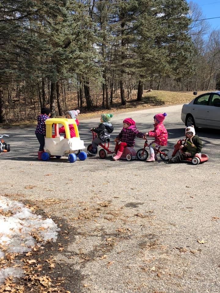 Adult and children on ride-on toys on an asphalt surface
