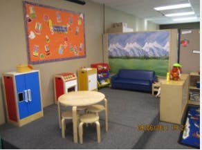 Playroom with small table and chairs, toy kitchen, and blue couch