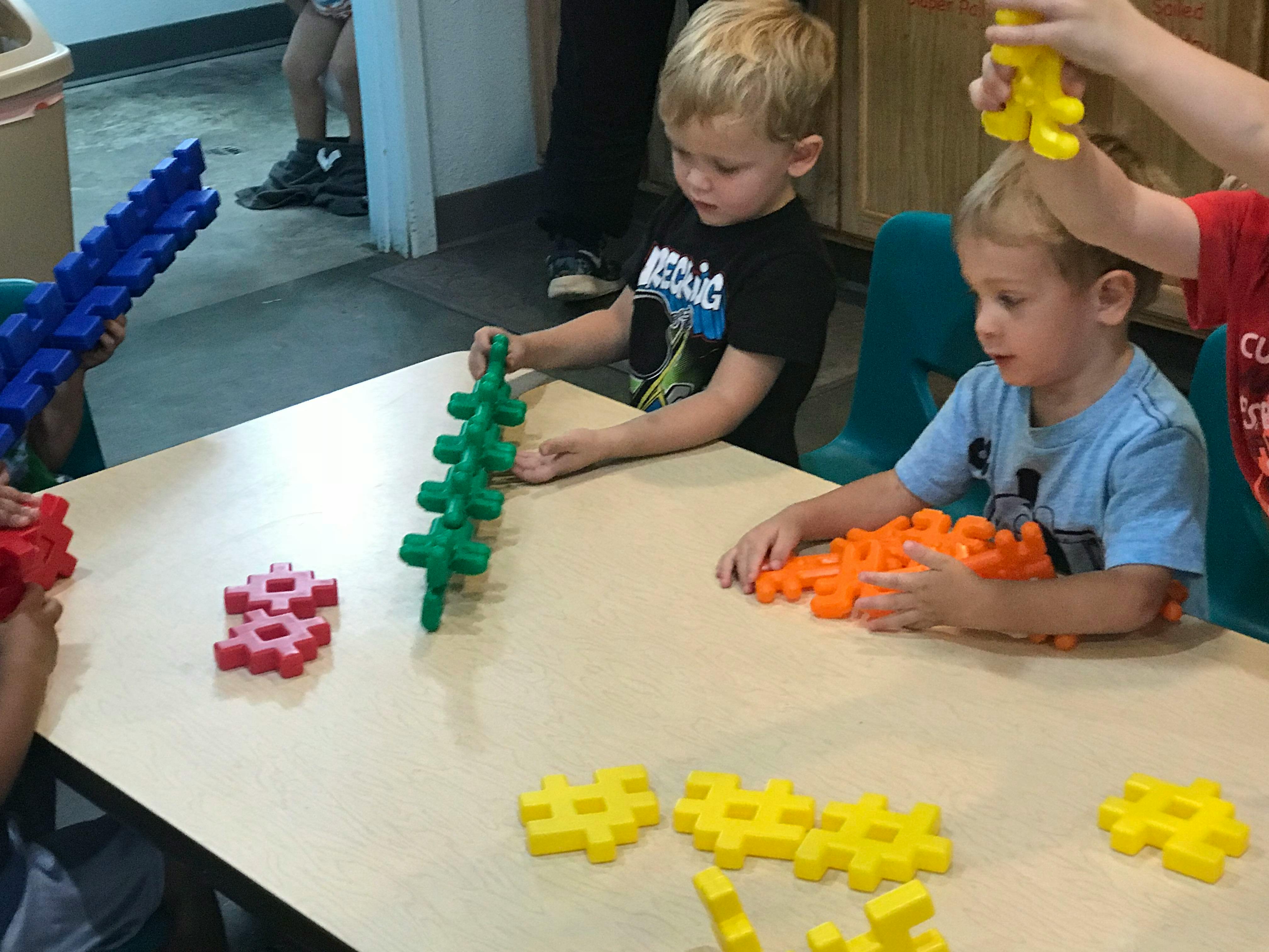 Children playing with colorful interlocking building toys at a table