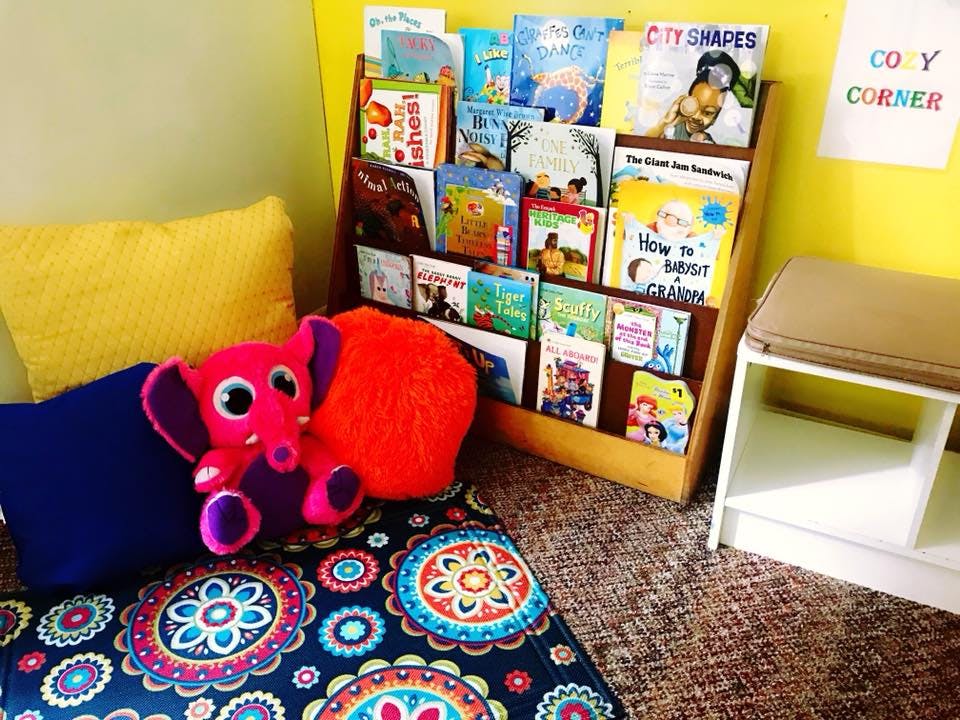 Children's book display with a plush elephant toy and pillows on a rug