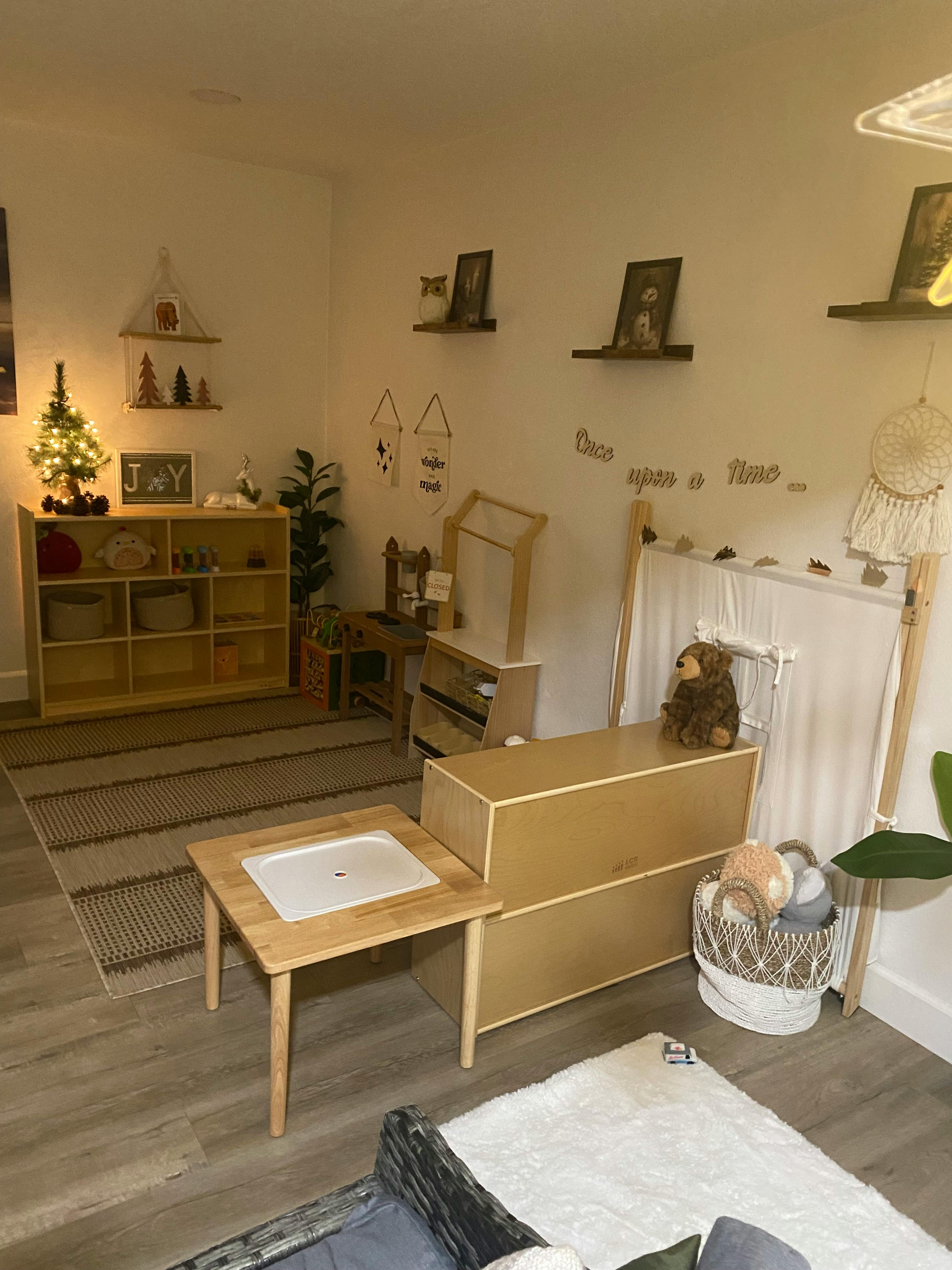 A room with a small Christmas tree, shelves, and wooden furniture