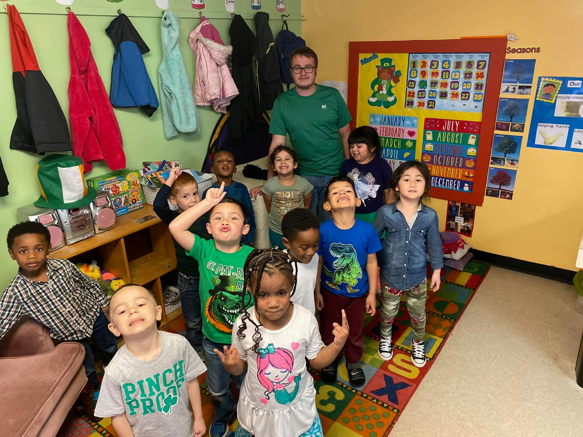 Adult and multiple children posing in a classroom