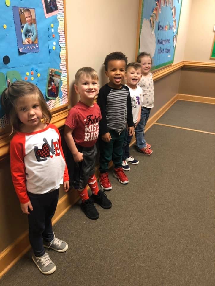 Five children standing in a line indoors