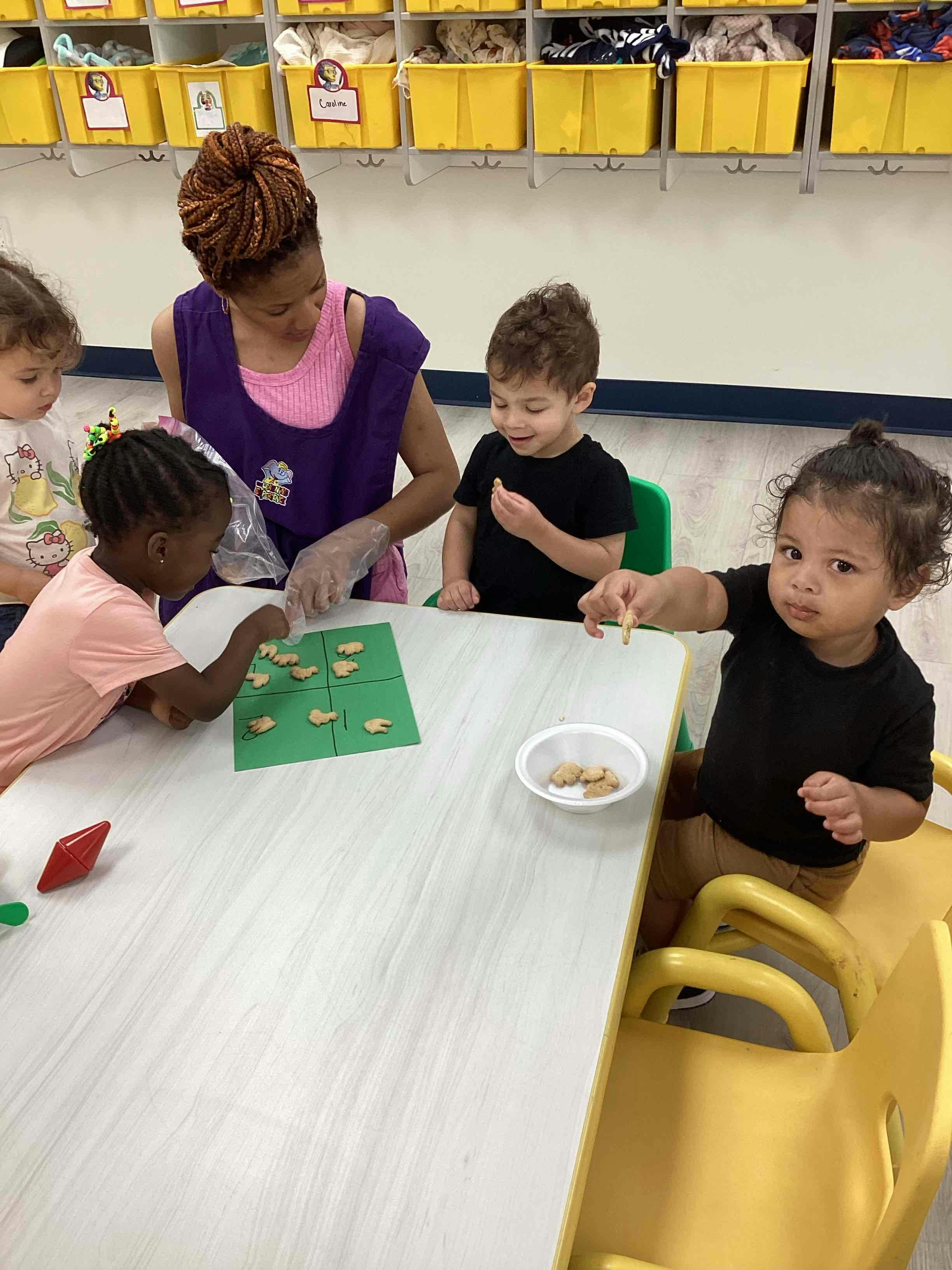 Adult and three children at a table with a game and a bowl of snacks