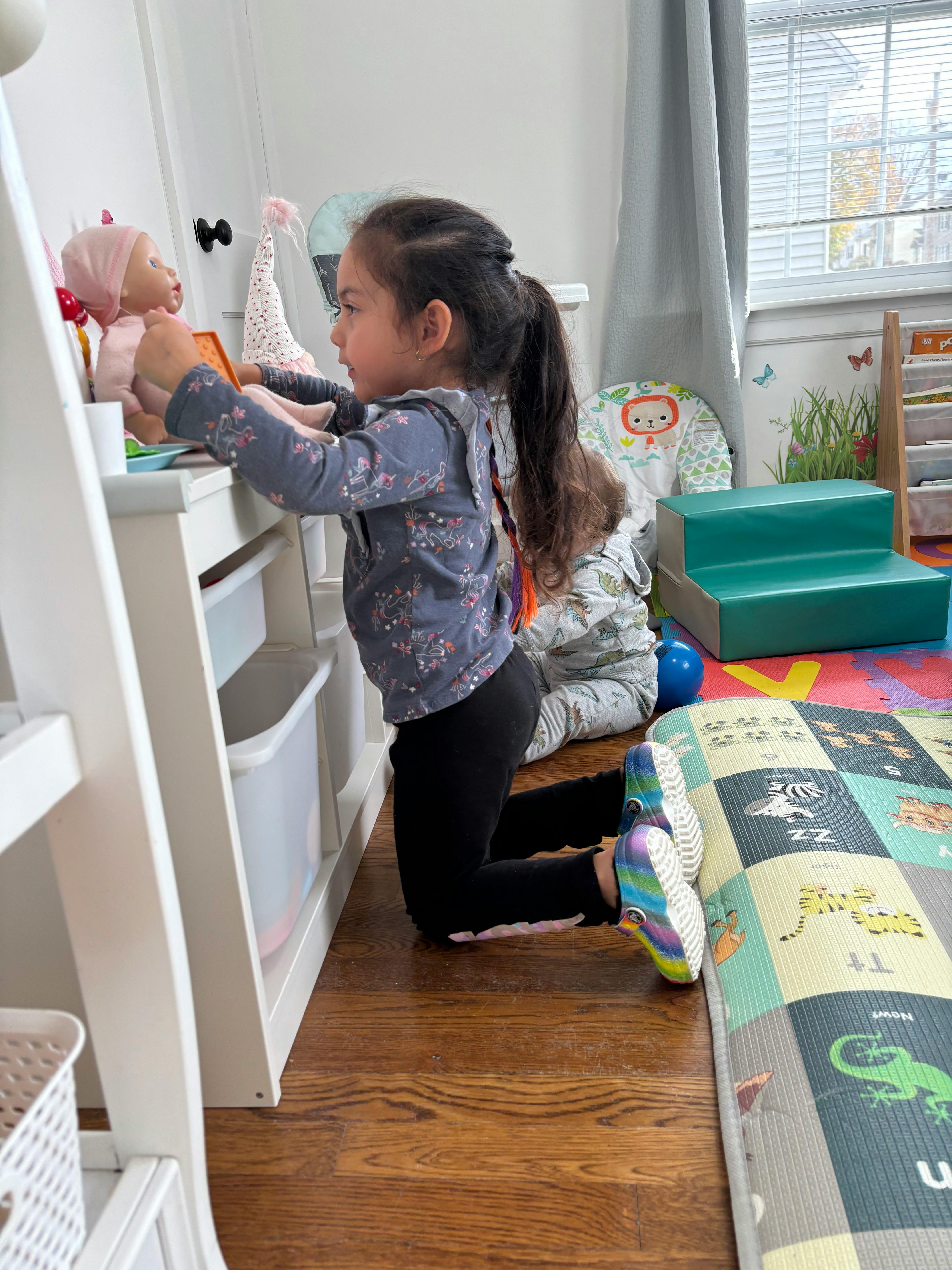 Child kneeling and playing with a doll