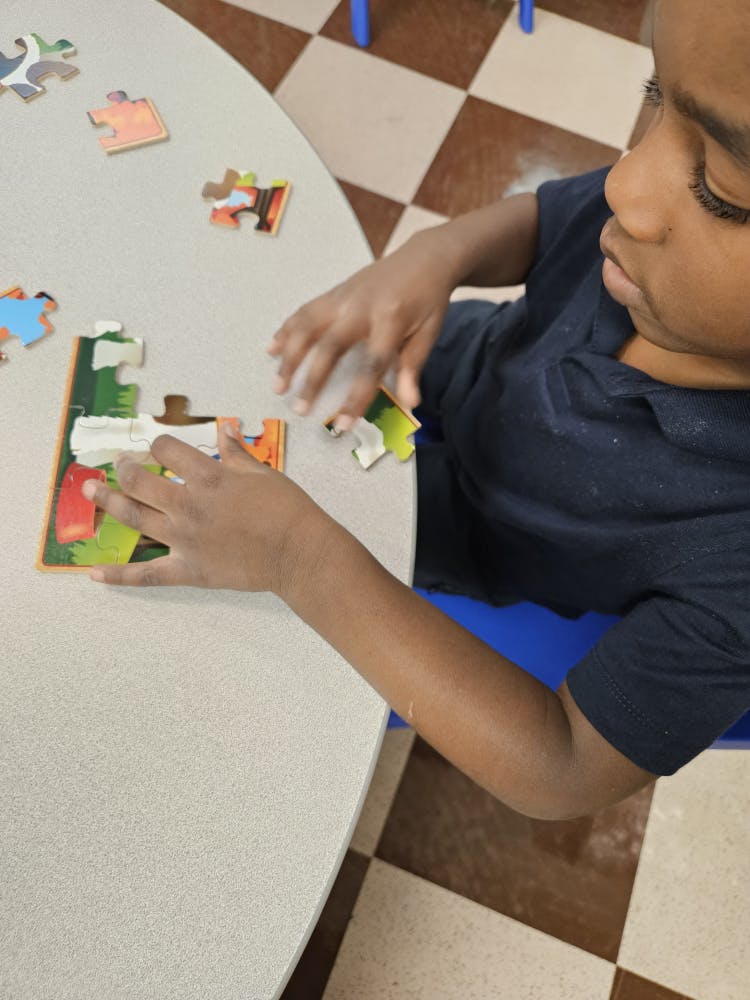 Child at a table working on a colorful jigsaw puzzle