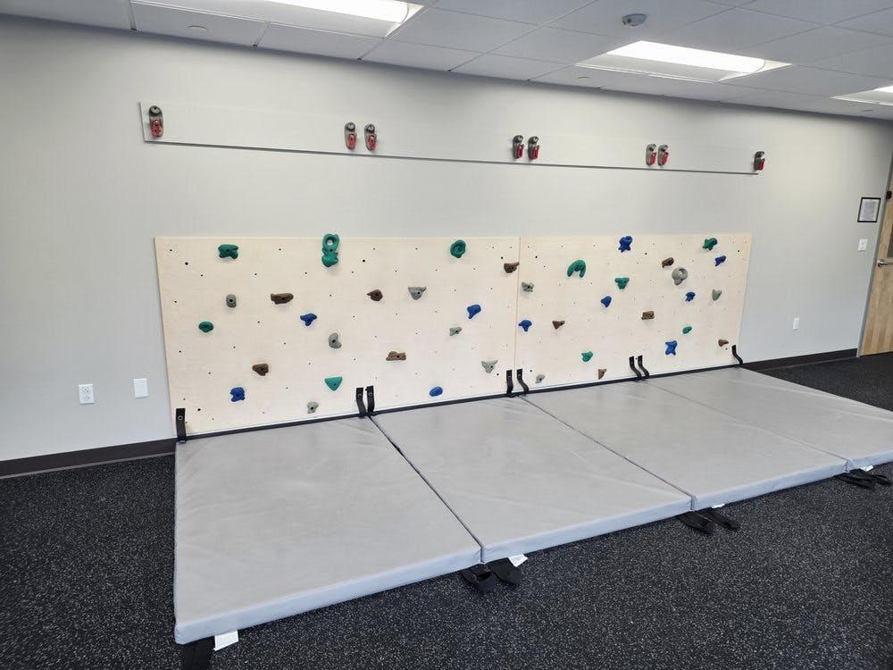 Indoor bouldering wall with gray mats on the floor