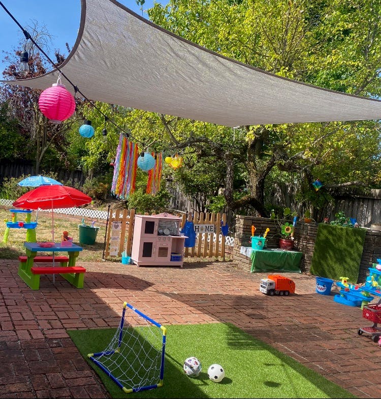 Backyard patio with children's toys including a soccer goal and play kitchen