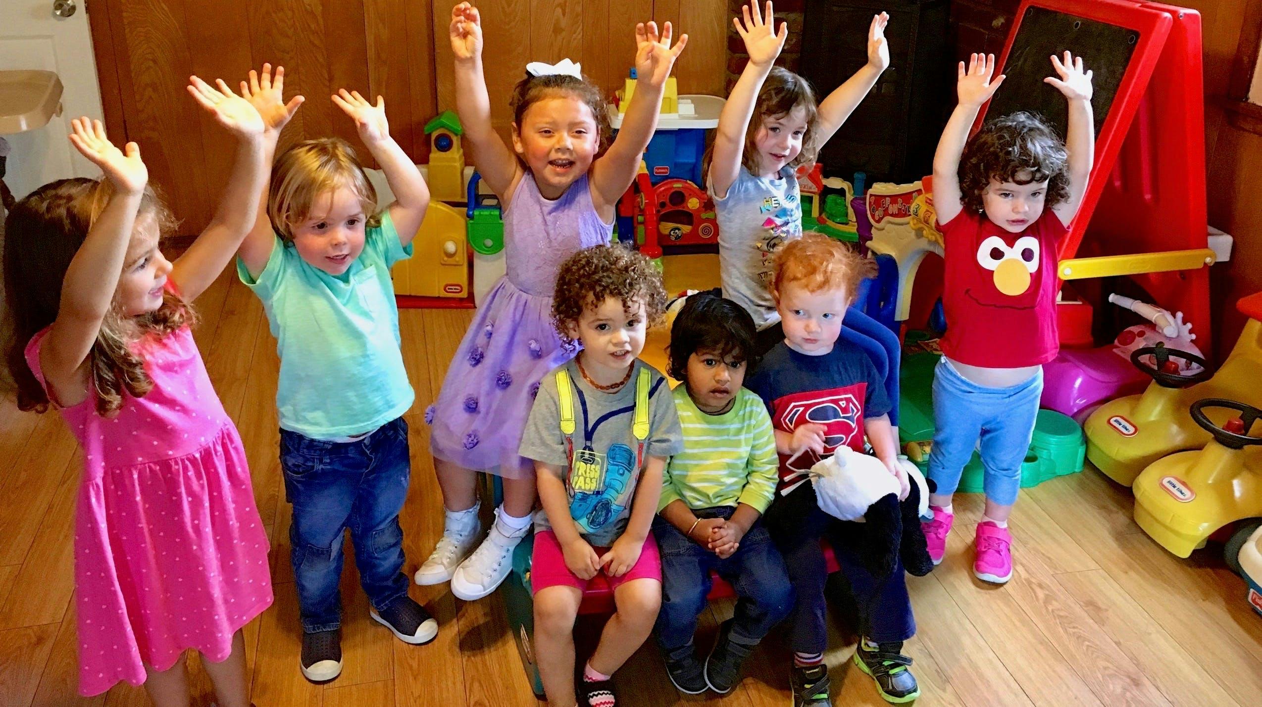 Group of children with hands raised in a classroom