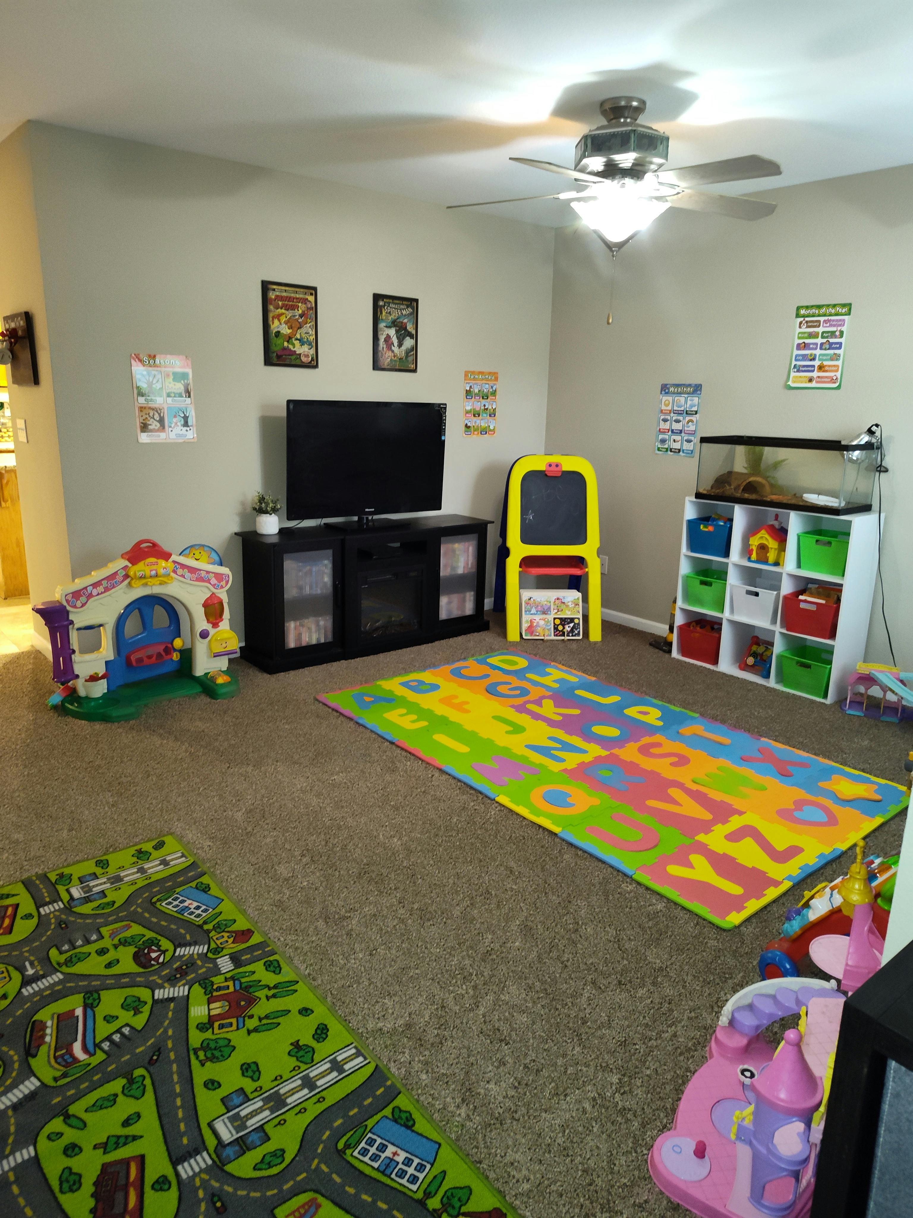 Playroom with a television, toy storage, and colorful playmats