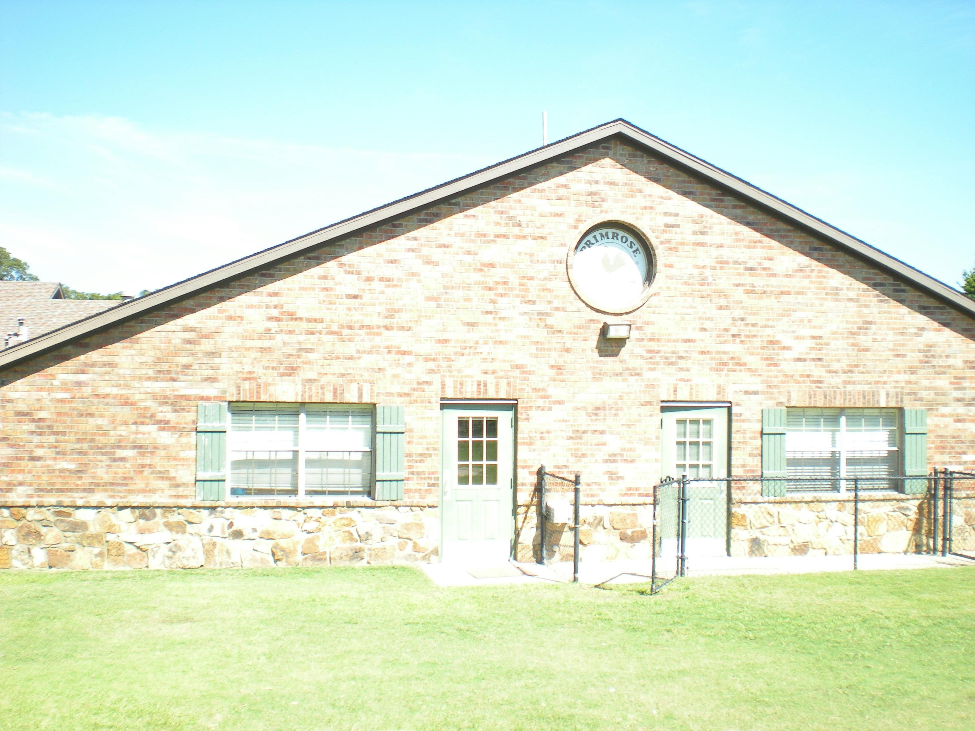 Brick building with two doors, two windows with shutters, and a round window