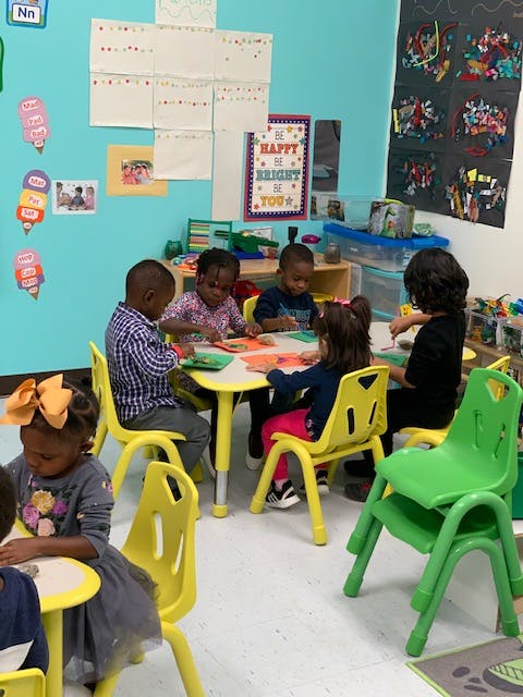 Children sitting at tables in a classroom, engaged in an activity