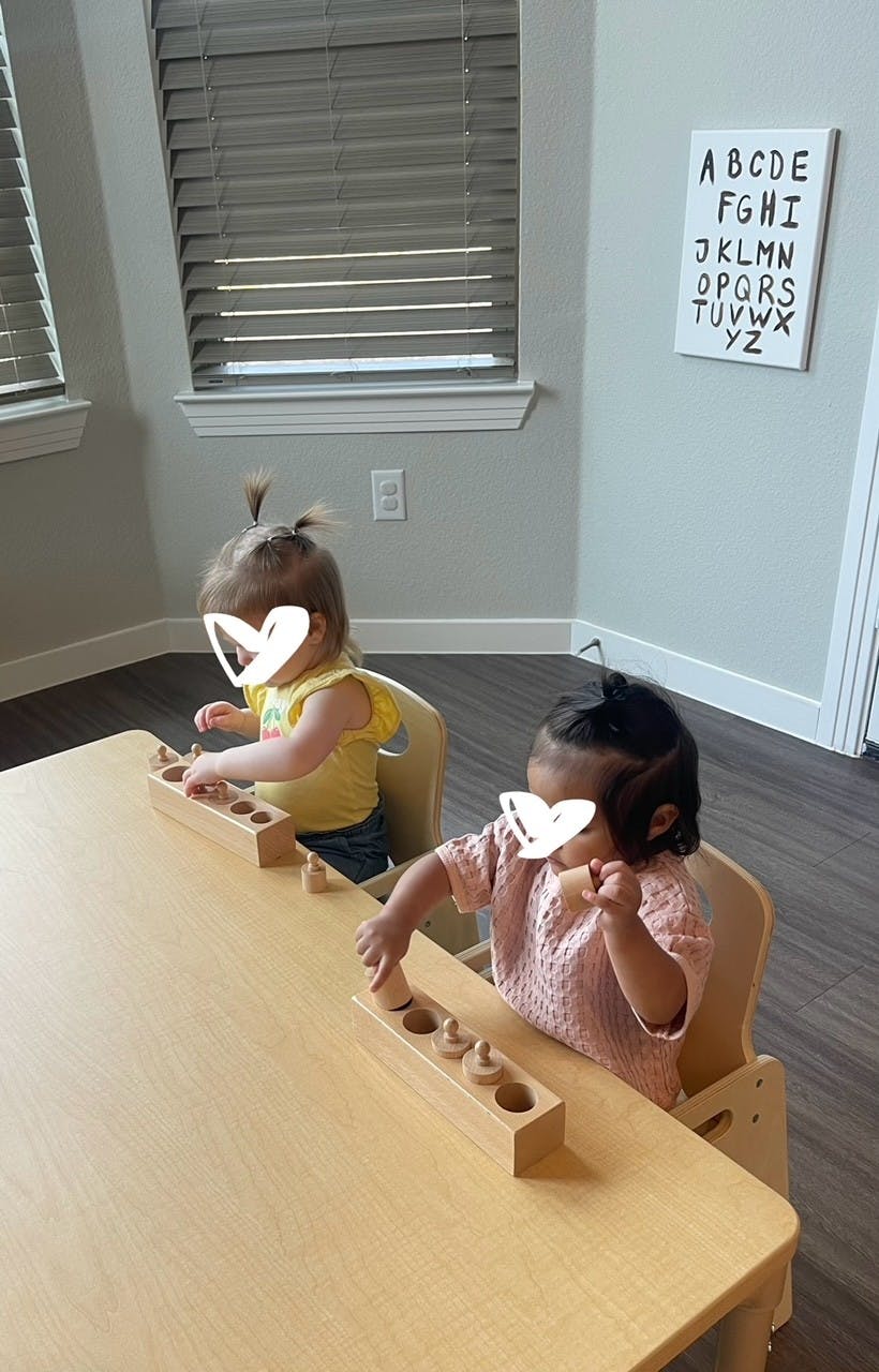 Two children playing with wooden cylinder blocks at a table