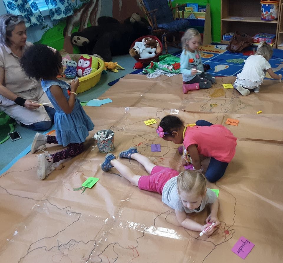 Children drawing on a large paper map on the floor