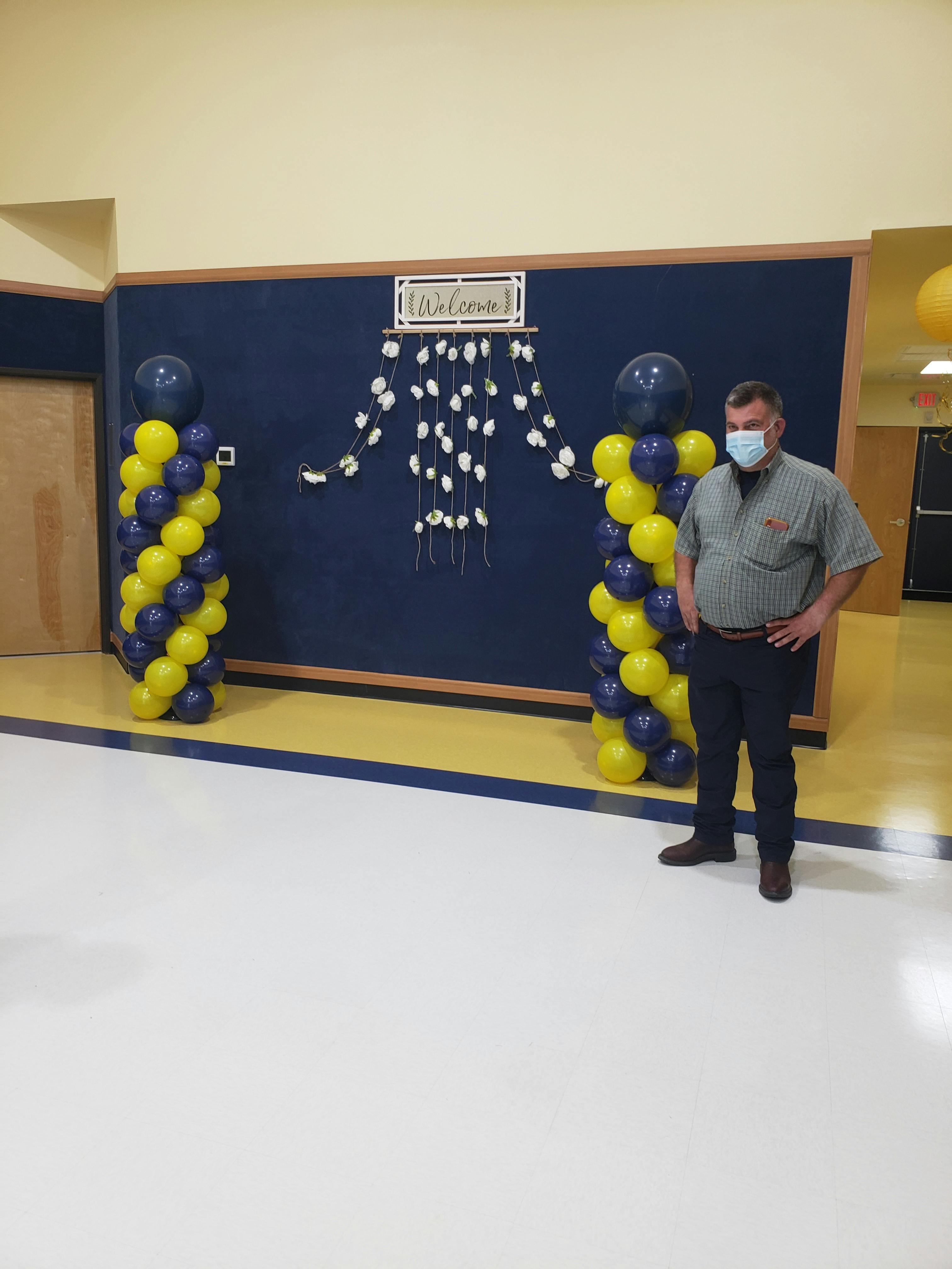 Person in a mask standing next to balloon columns