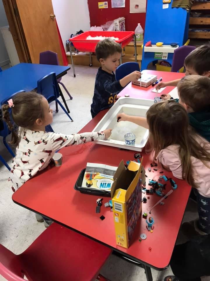 Children playing with toys at a red table