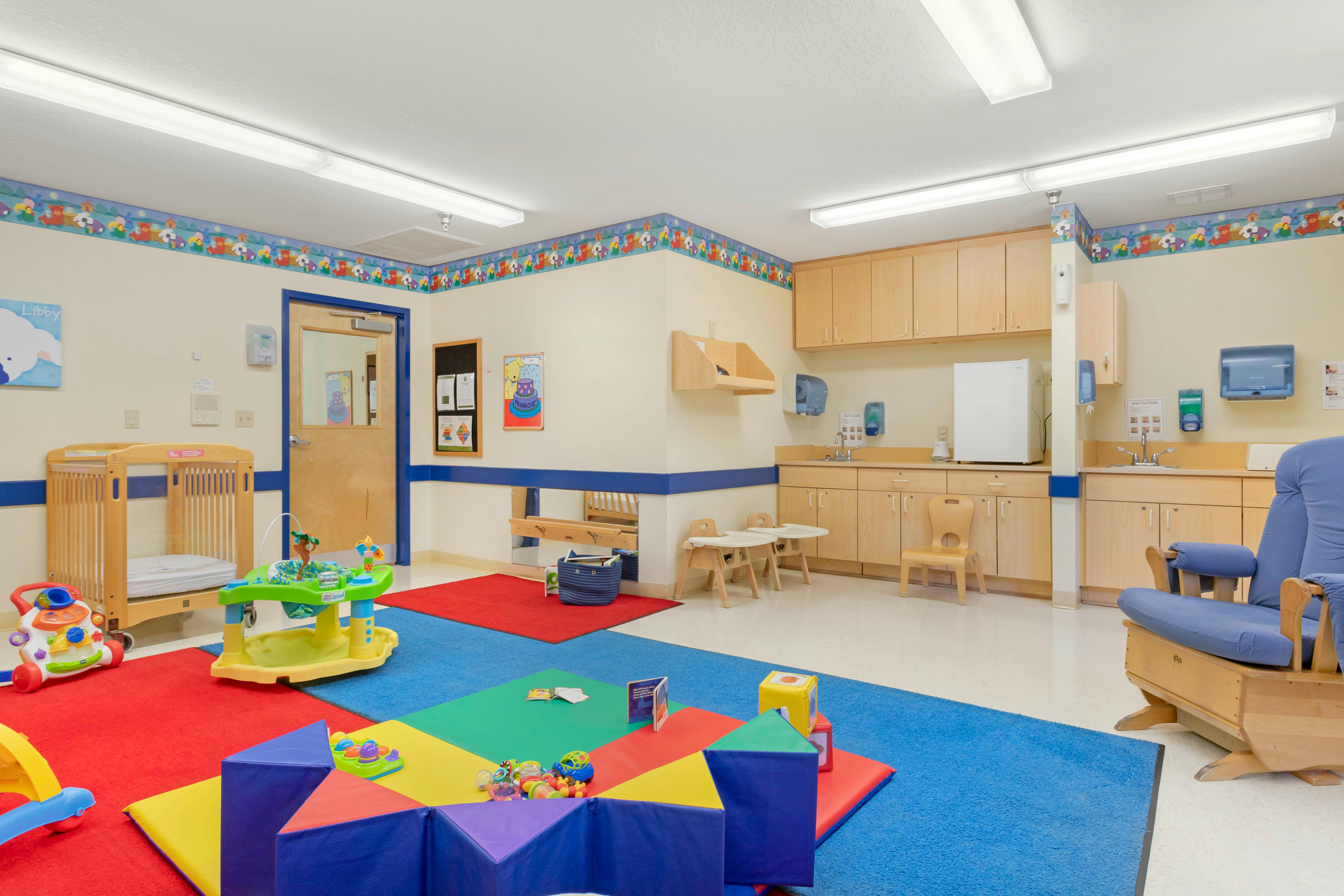 Baby nursery with colorful floor mats, crib, and kitchen counter with sink