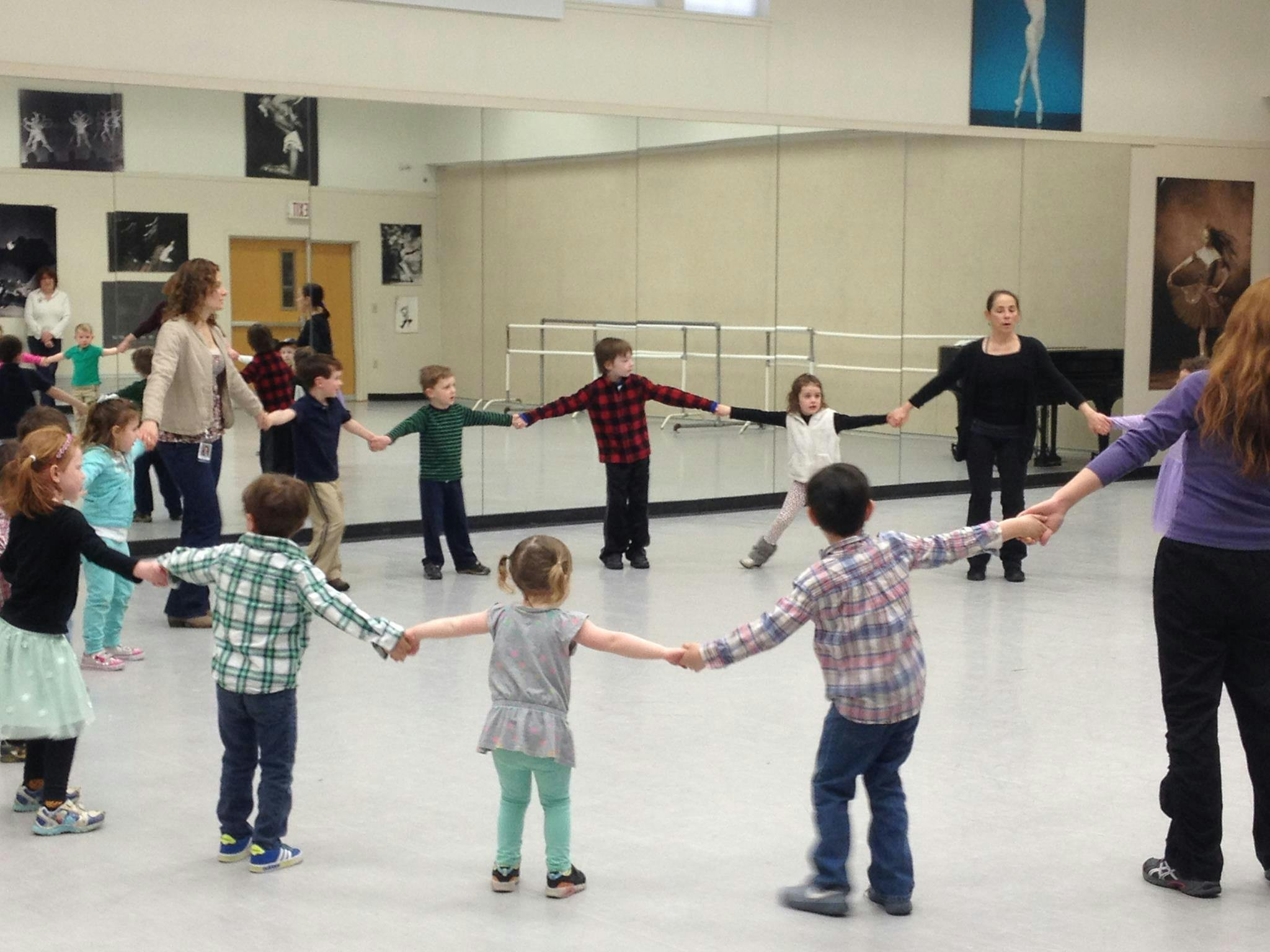 Adults and children holding hands in a circle in a studio