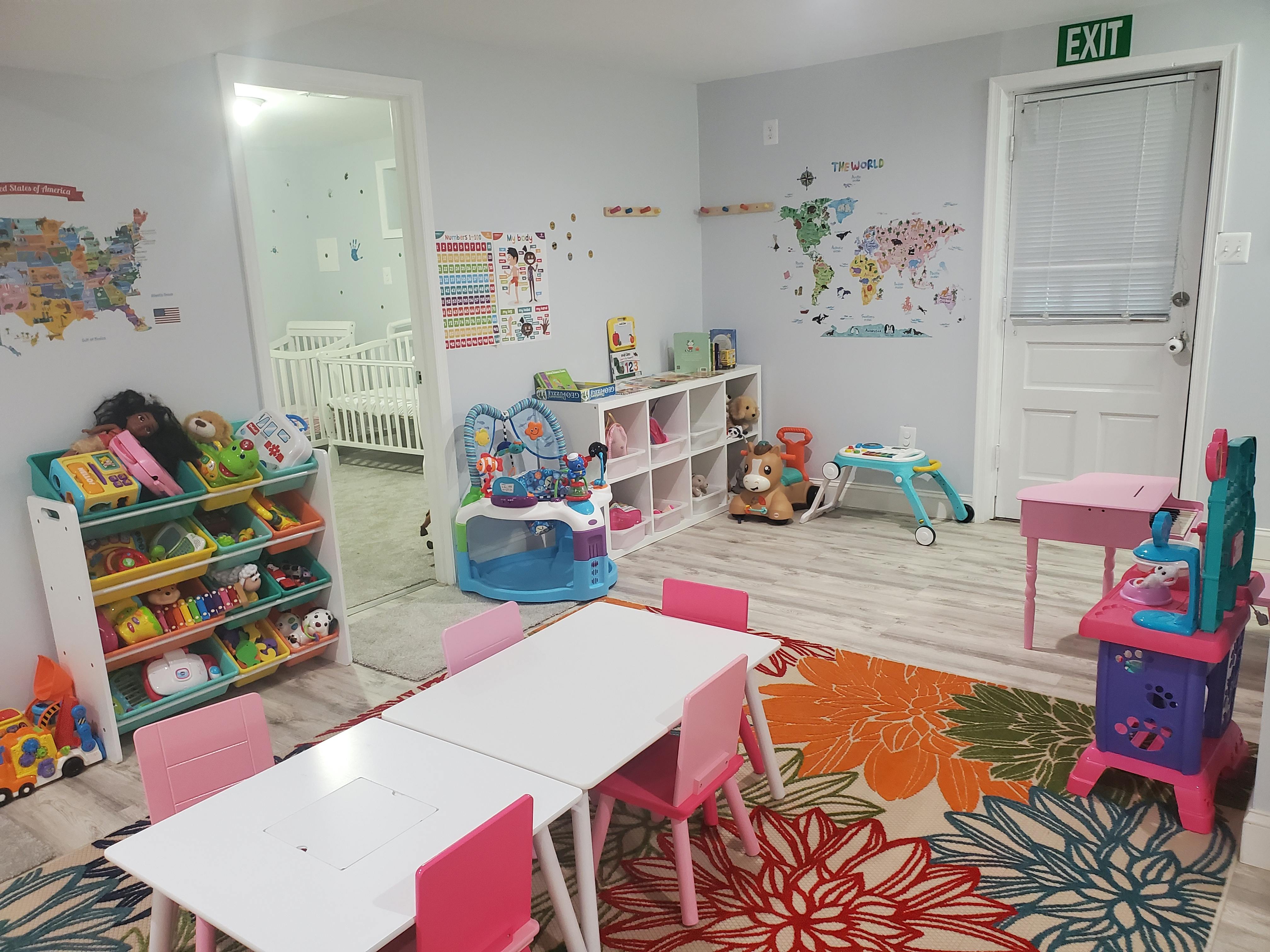 Playroom with small tables and chairs, toy shelves, and world map decals on wall