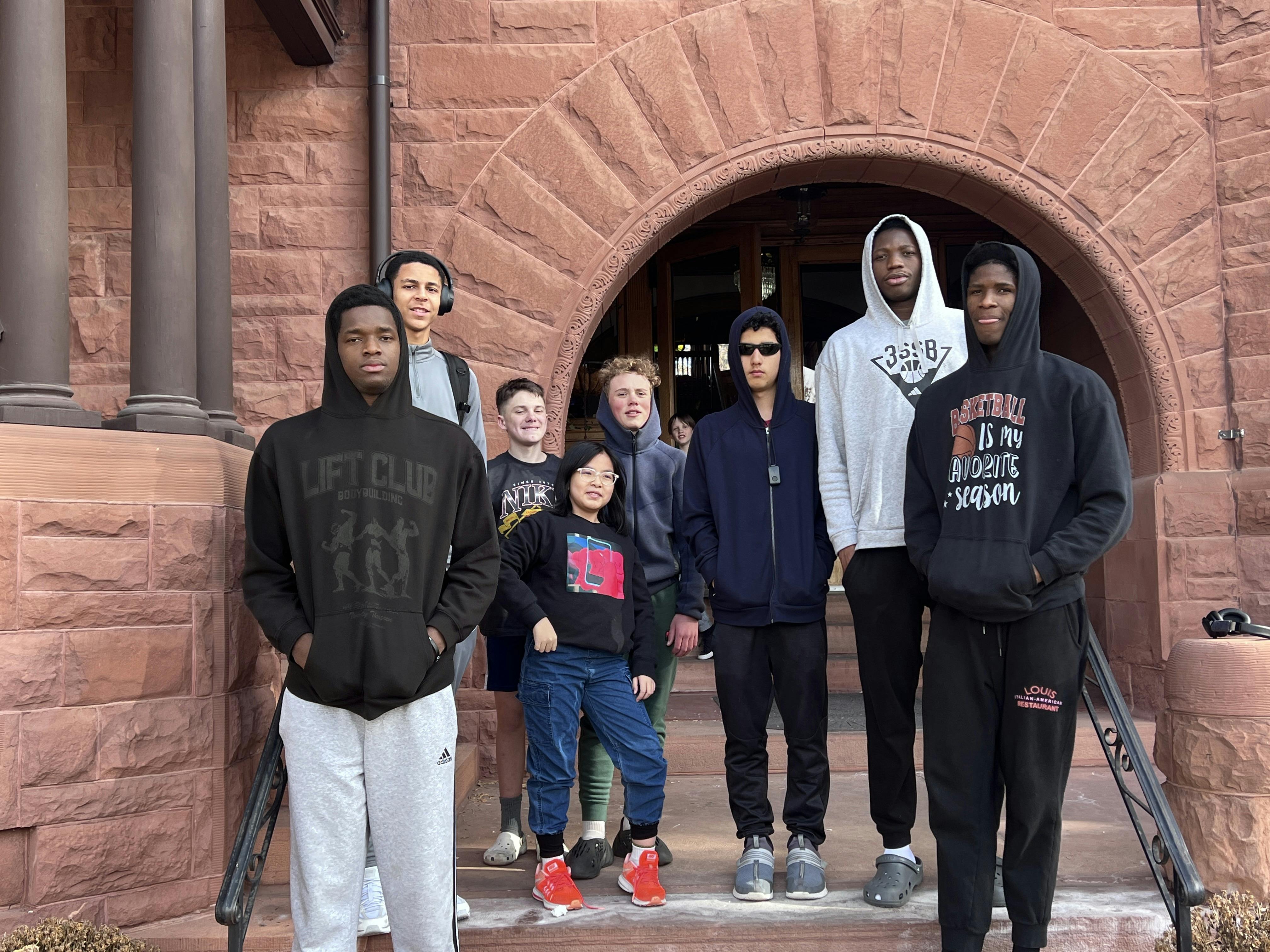 Group of teens and children standing on stone steps in front of an archway