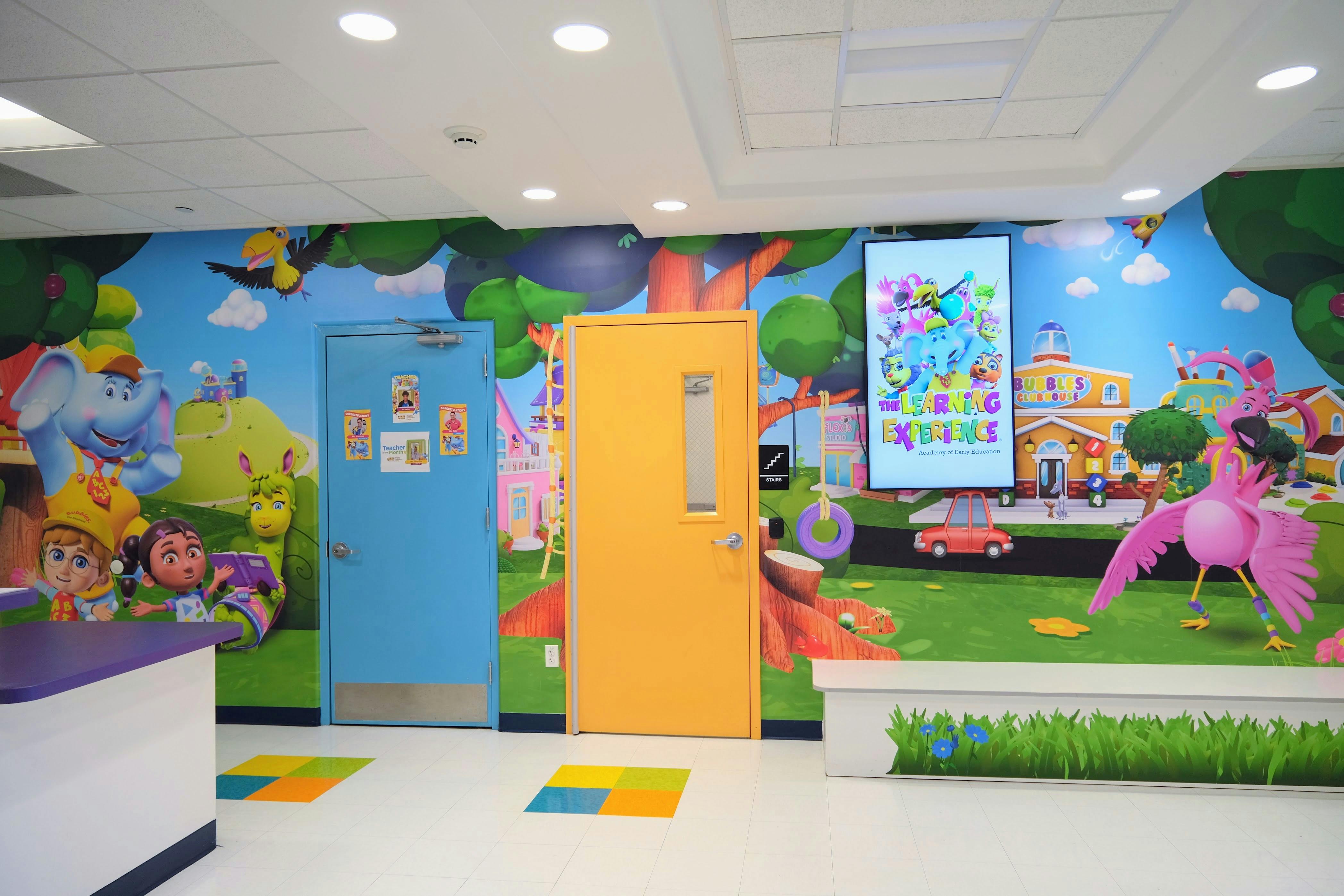 Colorful classroom hallway with blue and yellow doors and a wall mural