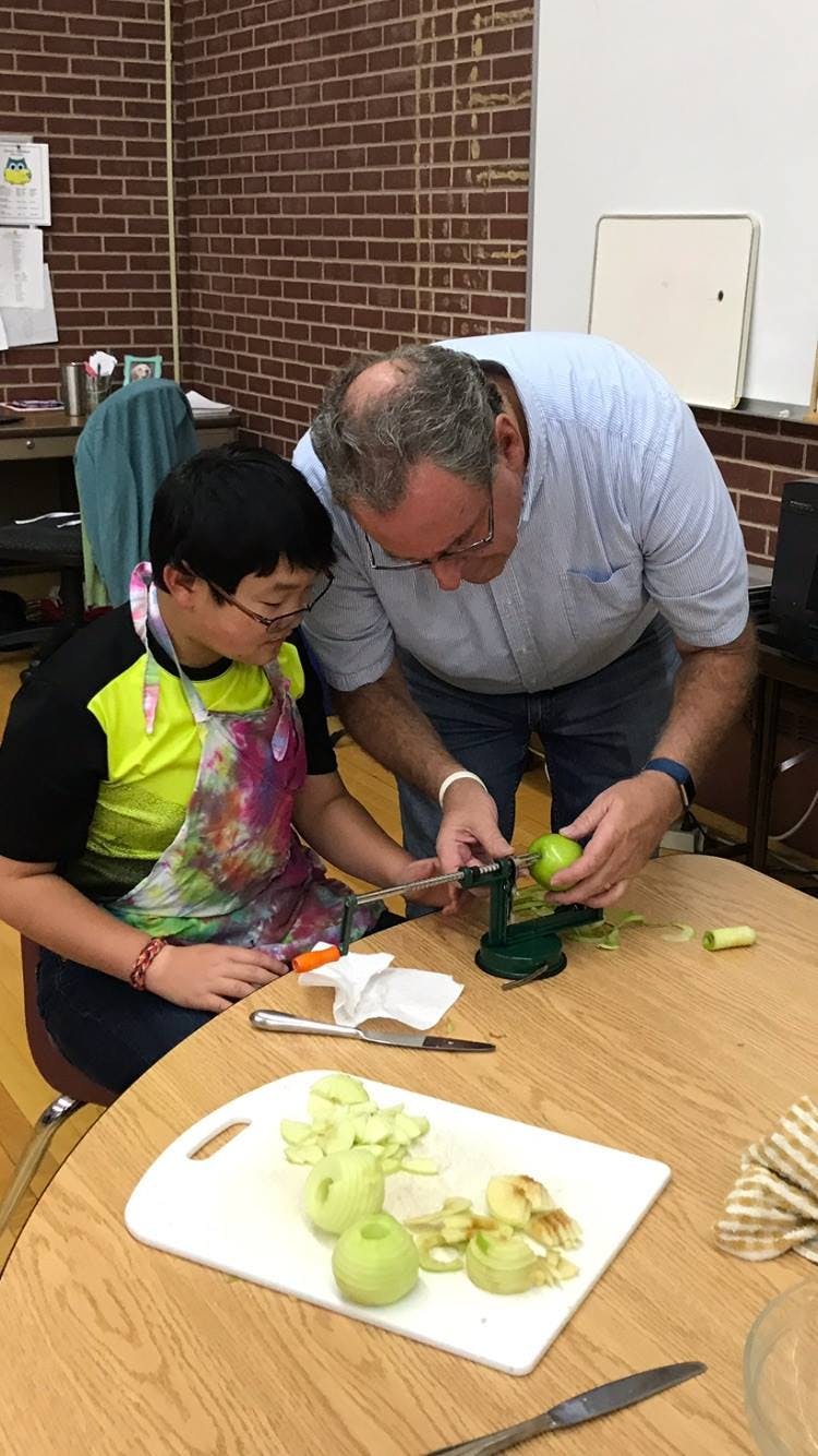 Adult and child peeling apples with a mechanical peeler