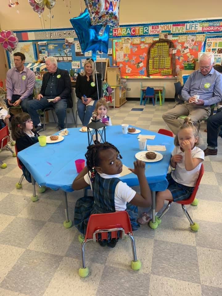 Adults and children sitting around a table in a classroom
