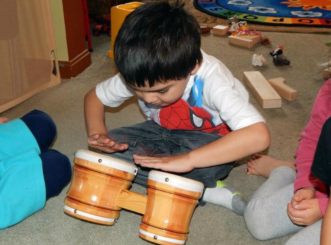 Child playing bongo drums on the floor
