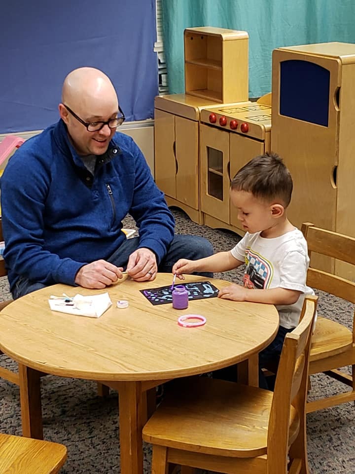 Adult and child sitting at a table doing an activity