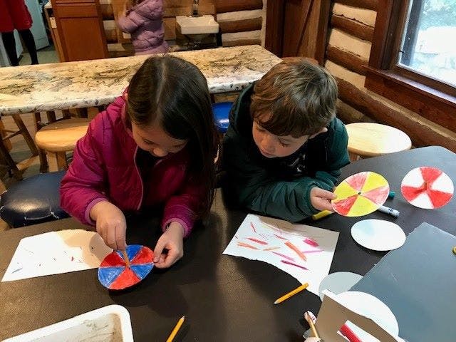Two children making paper crafts at a table