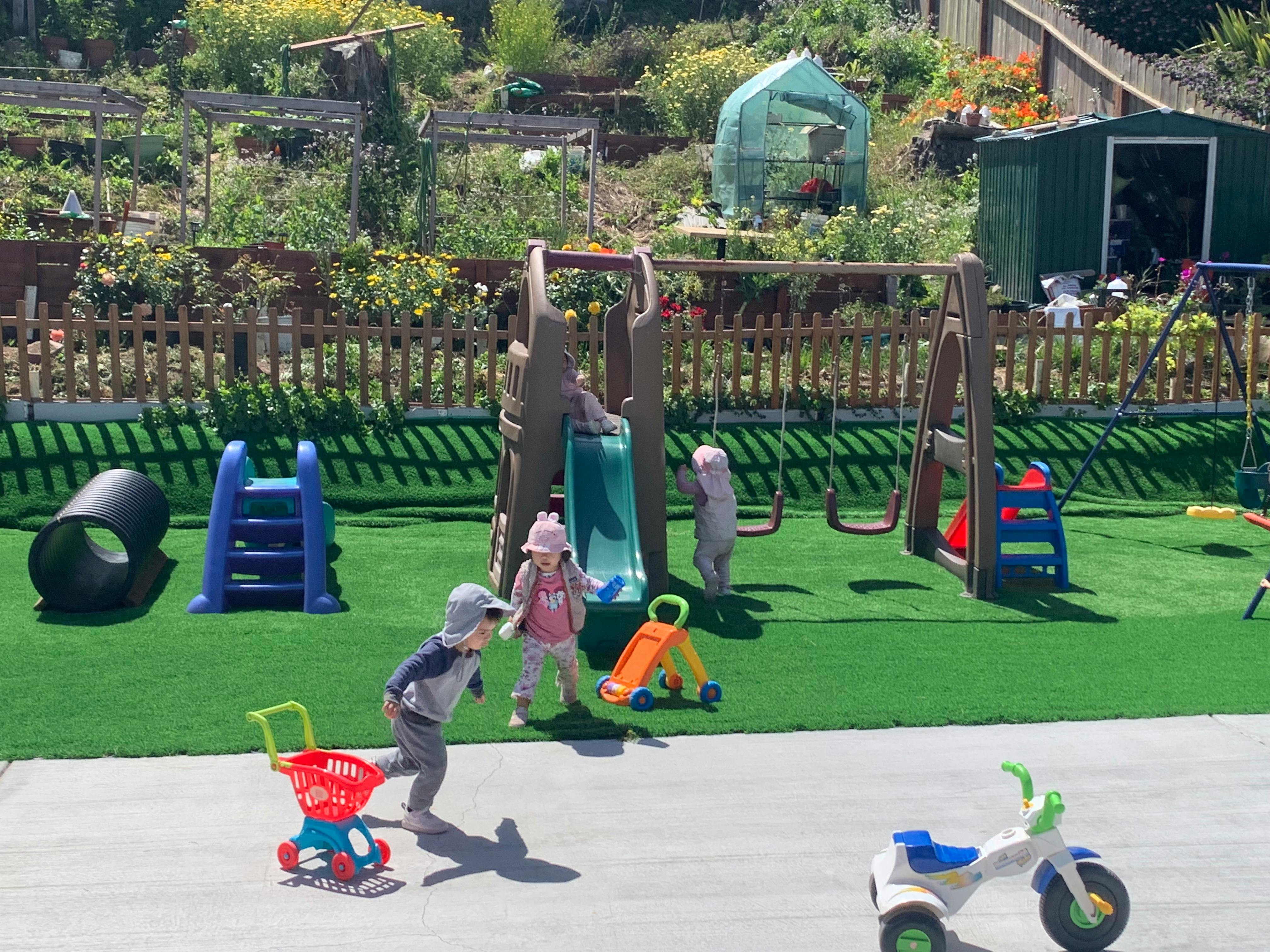 Children playing with toys and playground equipment in a yard