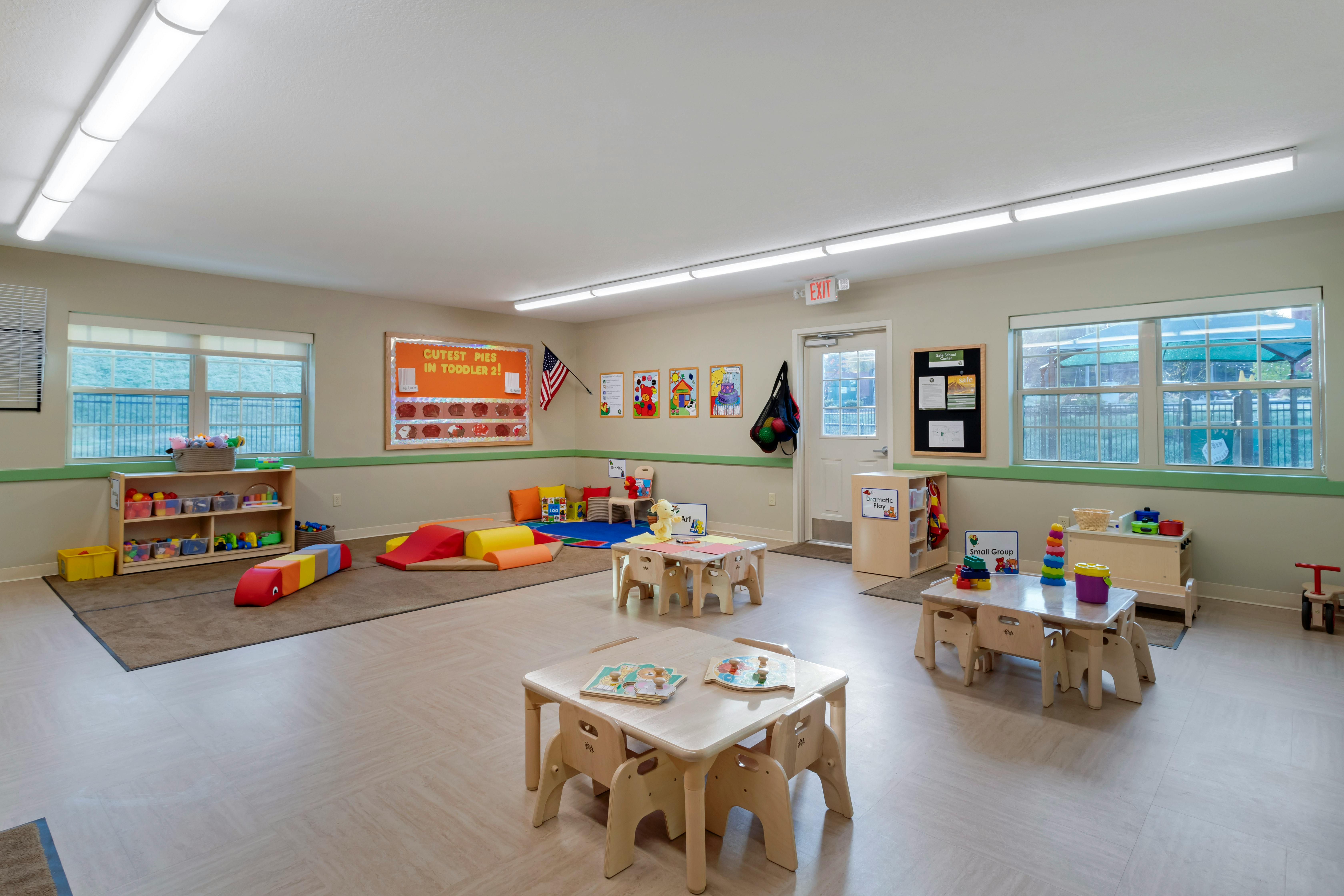 A colorful toddler classroom with small tables, chairs, and play areas