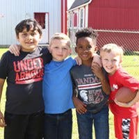 Four children standing together with arms around each other