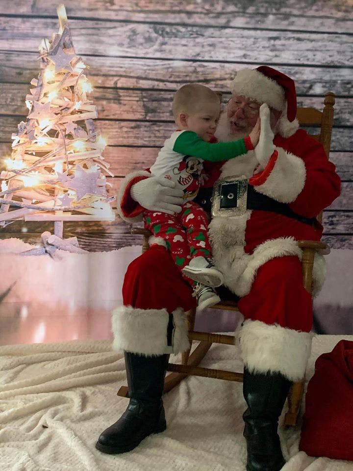 Child sitting on a person dressed as Santa Claus